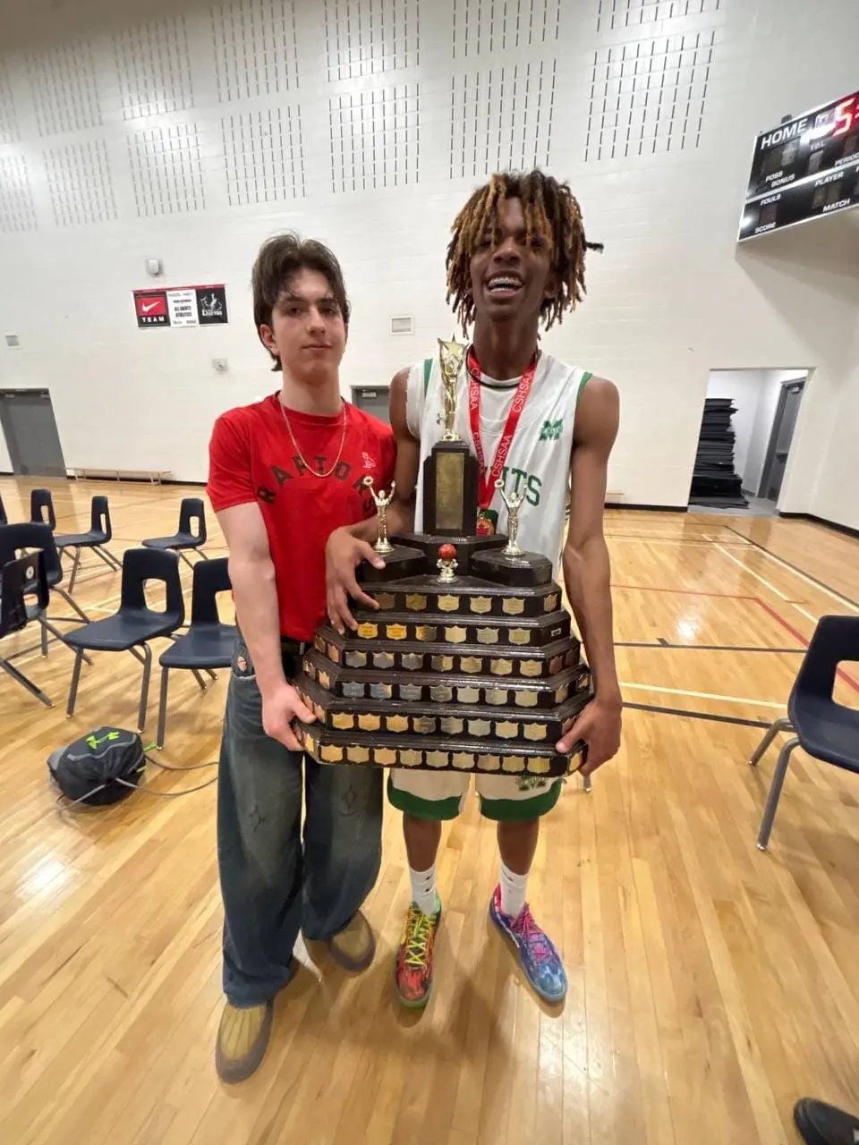 Simon Maxam with a friend holding a high school basketball championship trophy