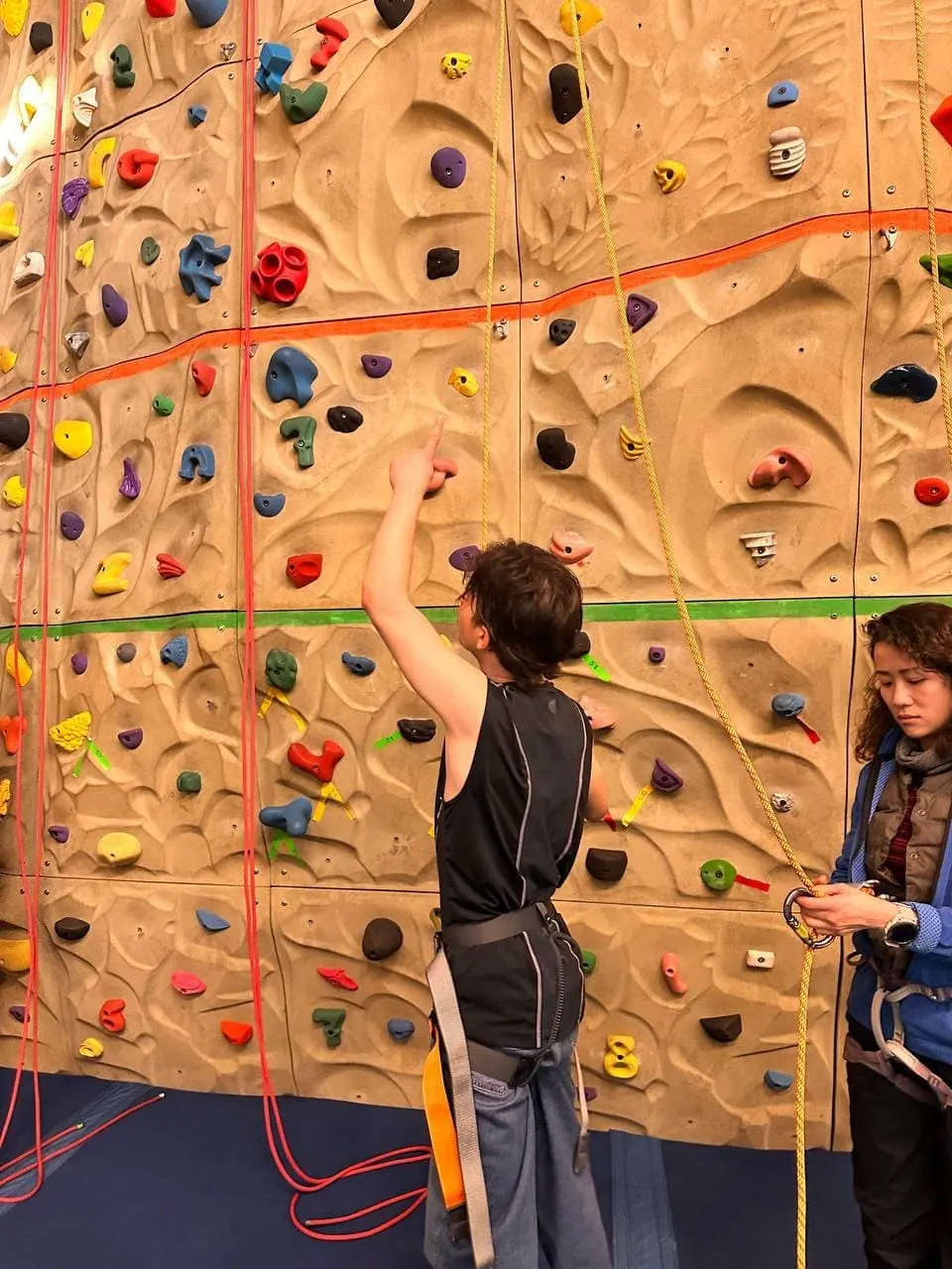 Simon Maxam on an indoor climbing wall, reaching for a hold