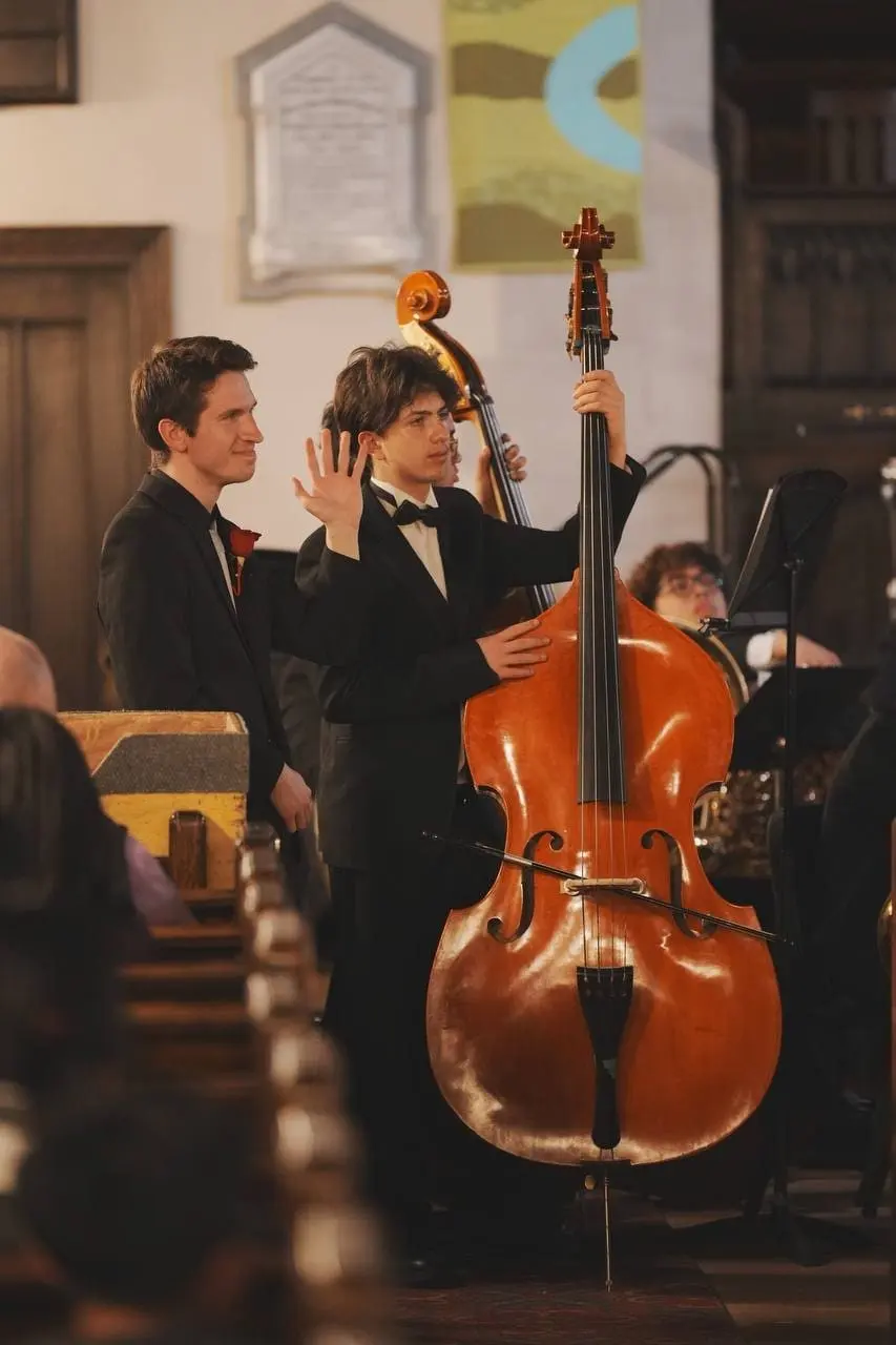 Simon Maxam playing double bass in a church performance, in a tuxedo