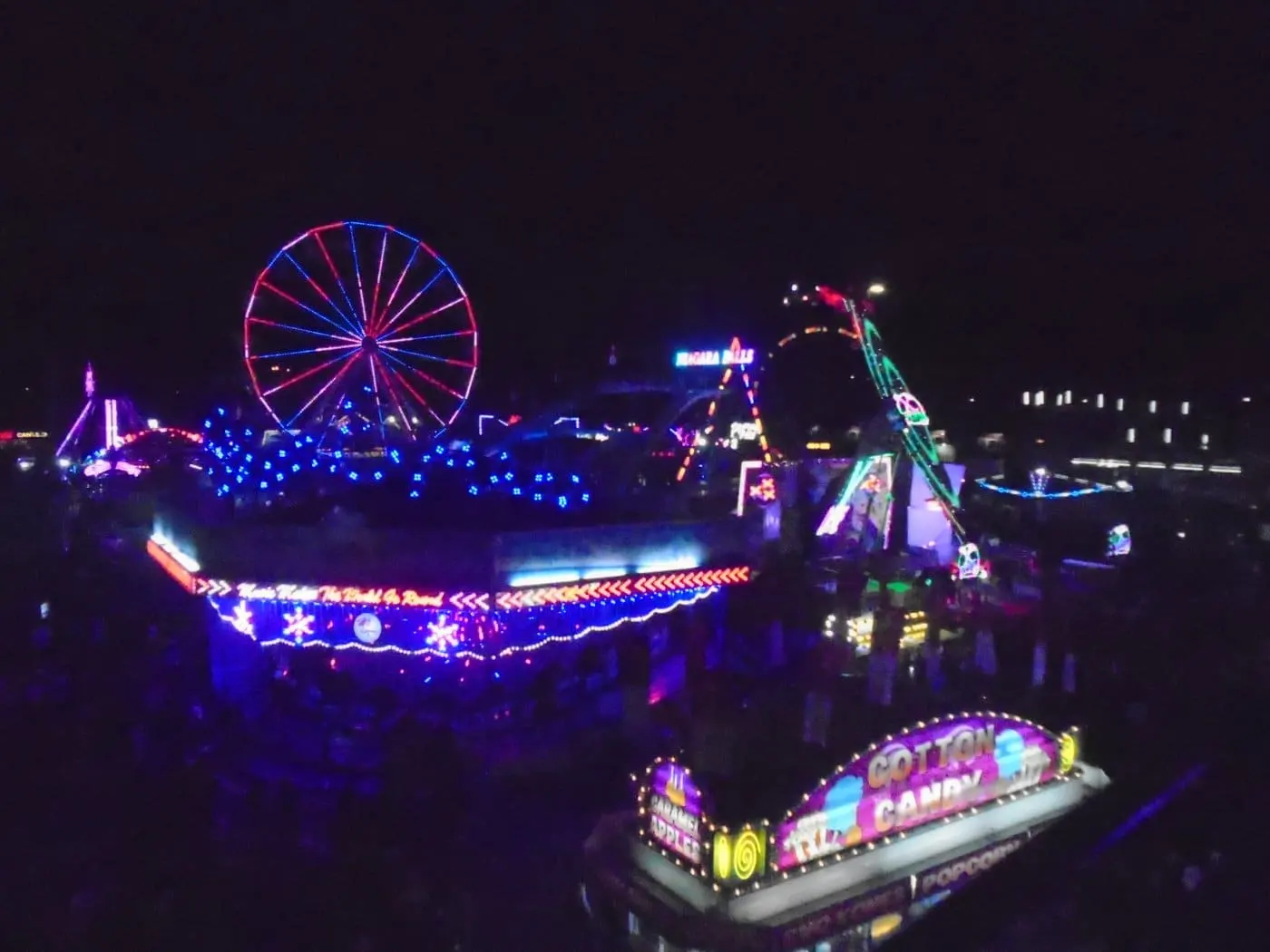 The Calgary Stampede midway lit up at night with the Ferris wheel and rides